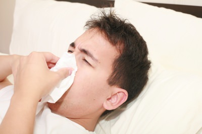 man in bed wiping his nose