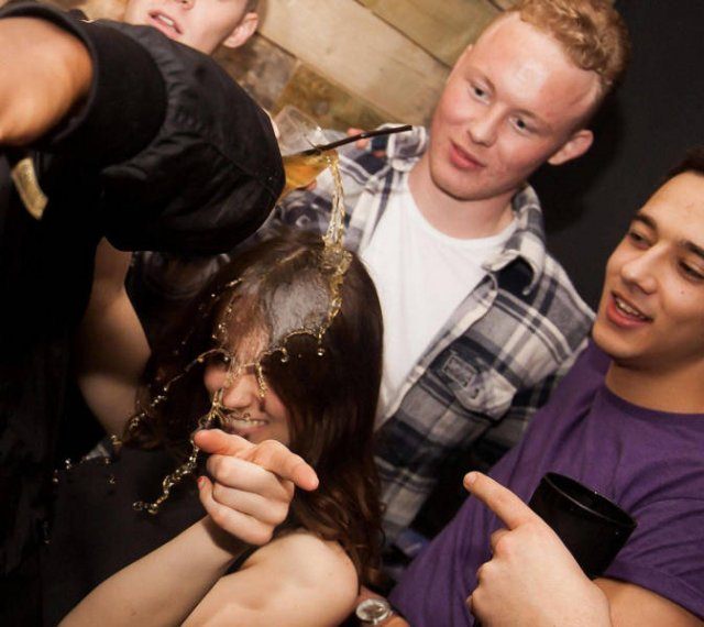 Photo taken at just the right time, girl posing and pointing at camera as a drink is spilled onto her head