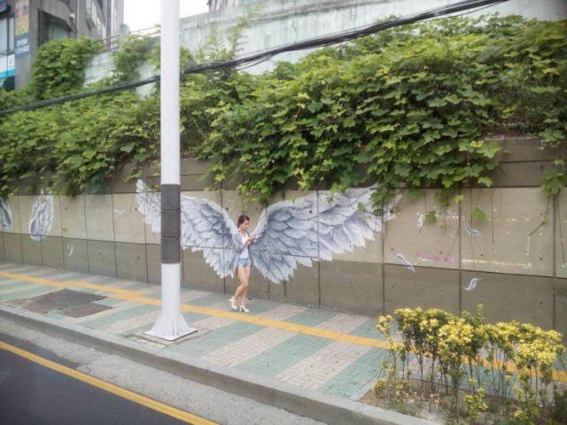 Photo taken at just the right time, girl on cell phone in from of grafitti wings