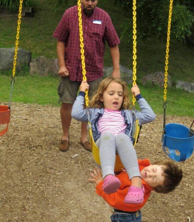 Photo taken at just the right time, little girl on swings kicks young boy