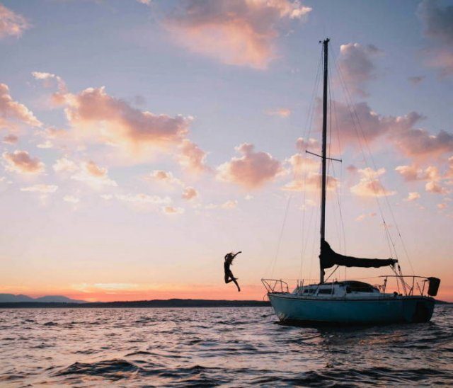 Photo taken at just the right time, girl jumping high off of a boat with her arms spread