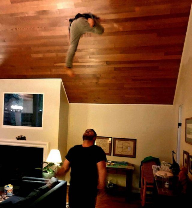 Photo taken at just the right time, man watches a person jump to the ceiling in a house