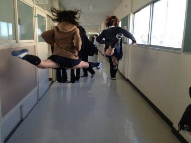 Photo taken at just the right time, two girls in skirts mid-air jumping into a split 
