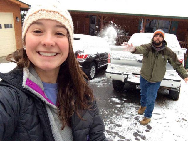 Photo taken at just the right time, girl taking a selfie as guy throws a snowball at her