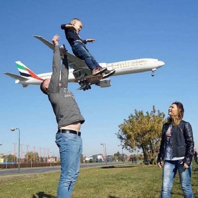 Photo taken at just the right time, parents playing with child while airplane passes in the background