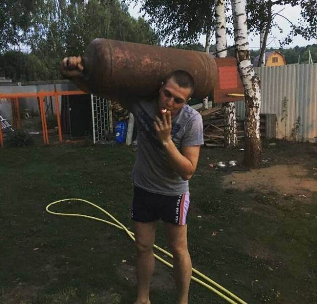 funny pictures of bad ideas, man holding a gas cylinder while smoking a cigarette