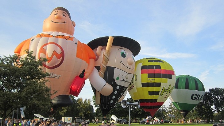 Different Hot air Balloons from Around the World, Four hot-air balloons, including "the world's largest refueling attendant" (far left) and "the world's largest carpenter" (second balloon from left) at the Barnstorfer Balloon Festival 2019