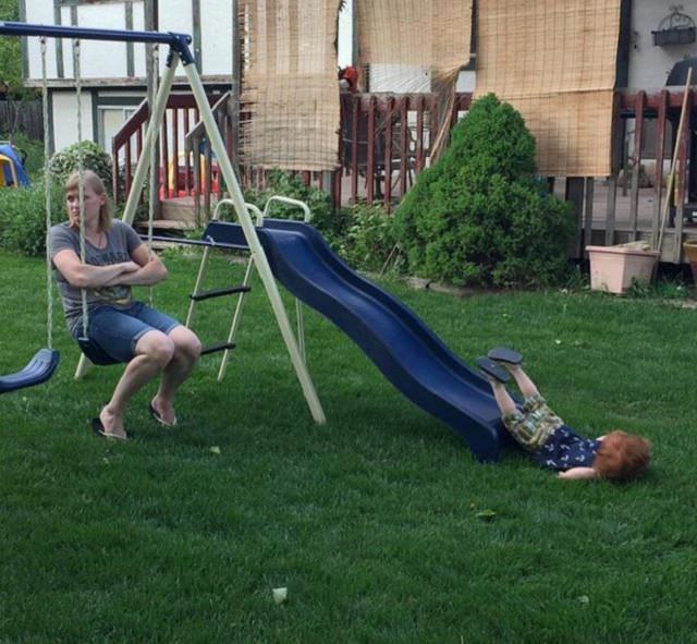 Perfectly-timed Photographs, mom sitting on swing looking away as child coming down the slide falls to the ground