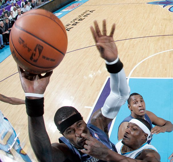 Perfectly-Timed photographs, two basketball players attempting to land a shot, with one player's fingers in the nose of the other player