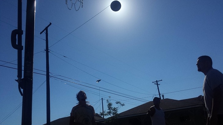 Perfectly-timed photographs, people playing basketball, with the basketball covering the sun forming an eclipse