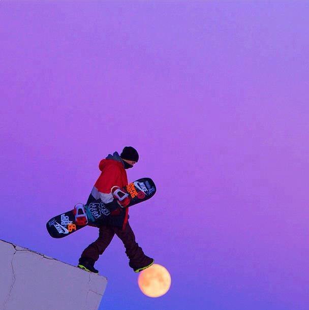 Perfectly-Timed photographs, man with snowboard stepping of ledge of mountain with his foot over the outline of the moon