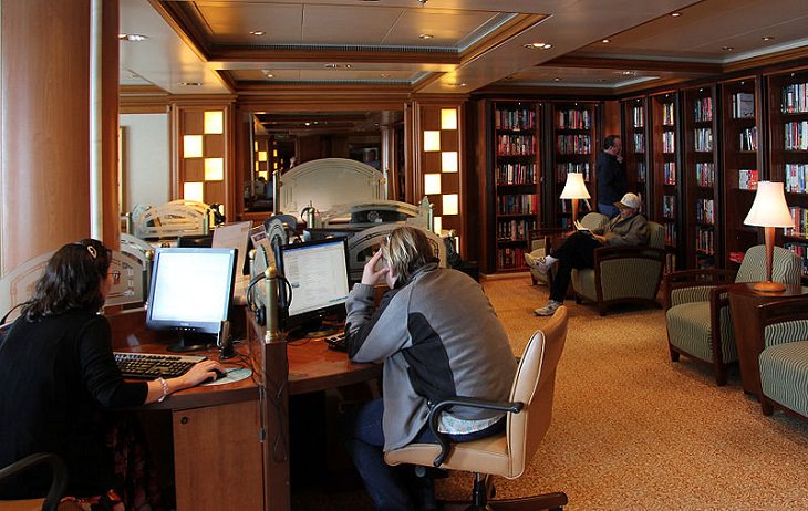 Tips for making the most of your next cruise trip, people sitting at computers in a cruise ship library 