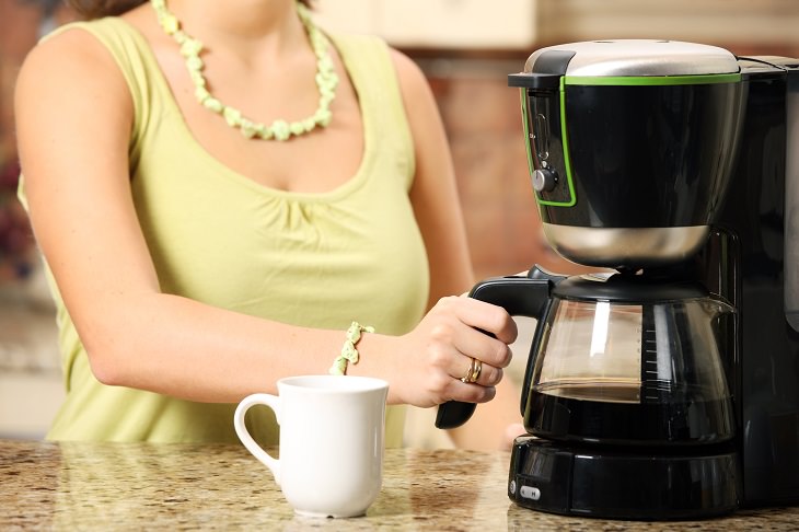 different methods of coffee stain removal, woman in yellow dress holding a coffee pot in a coffee maker