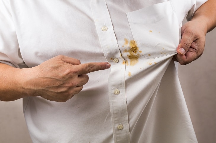 different methods of coffee stain removal, man wearing white shirt pointing at a dried brown coffee stain on the shirt
