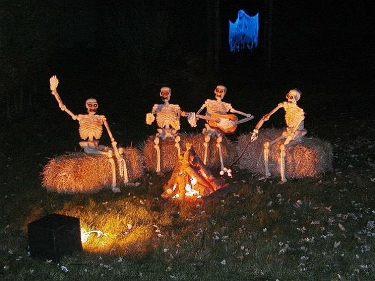 Most Incredible Halloween Decorations, skeletons sitting on hay around a bonfire, one playing guitar