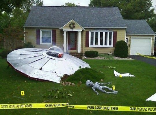 Most Incredible Halloween Decorations, decoration of spaceship crash landed in front of a house with an alien lying on the lawn