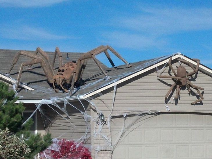 Most Incredible Halloween Decorations, two giant spiders climbing and hanging off different parts of the roof of a house