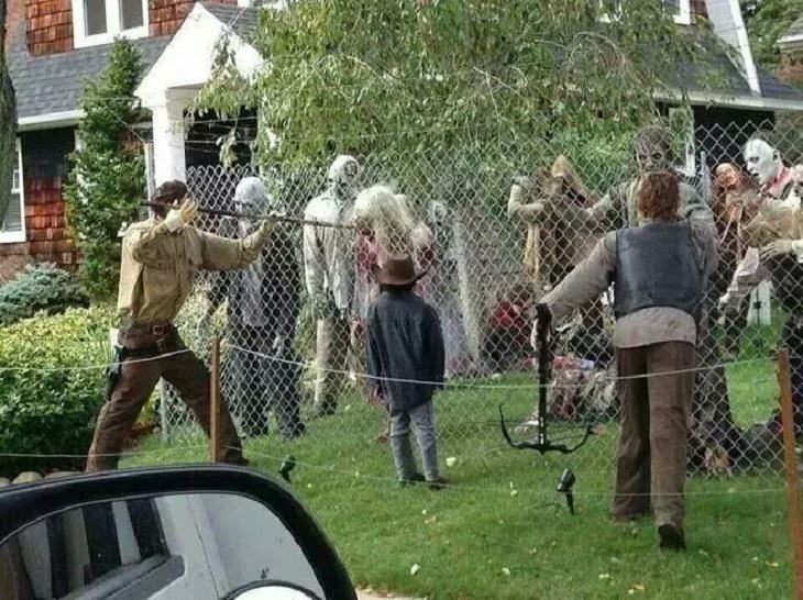 Most Incredible Halloween Decorations, decoration made to resemble The walking Dead with zombies behind a fence and two people on the other side of the fence with guns