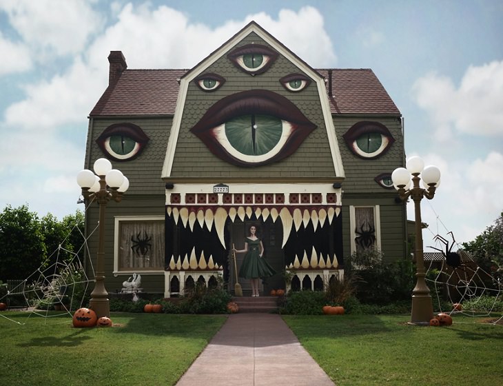 Most Incredible Halloween Decorations, Monster house with multiple eyes, sharp teeth and a witch with a broomstick standing at the entrance