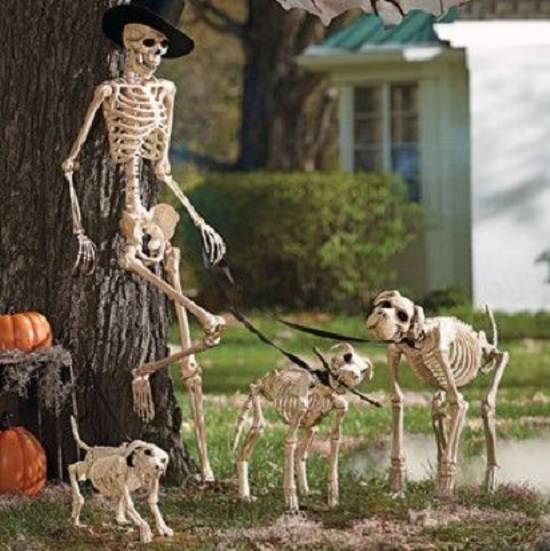Most Incredible Halloween Decorations, Skeleton man in a top hap leaning on a tree with his skeleton dogs on leashes