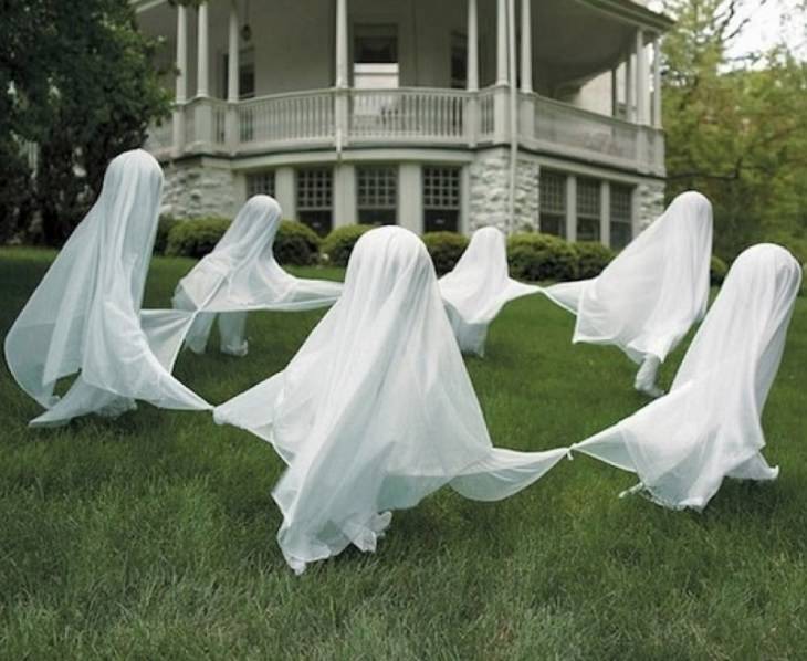 Most Incredible Halloween Decorations, ghost figures under white cloaks in a garden