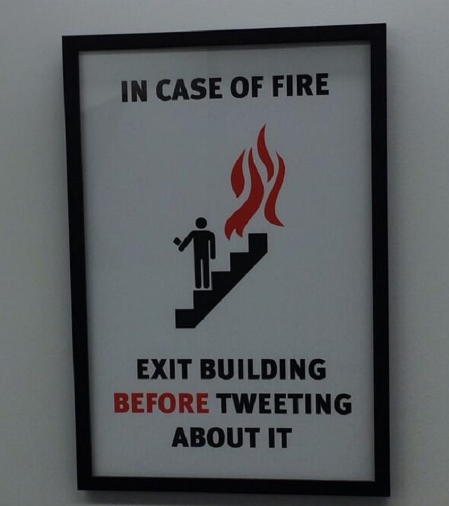 Funny warning and caution signs, warning stating that in case of fire the building should be exited before tweeting about it