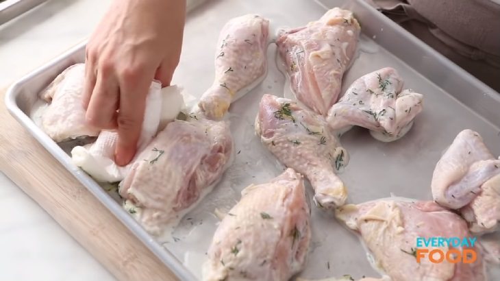 Simple and easy recipe for golden chicken with buttermilk marinade, marinaded chicken on a tray being pat down with napkin