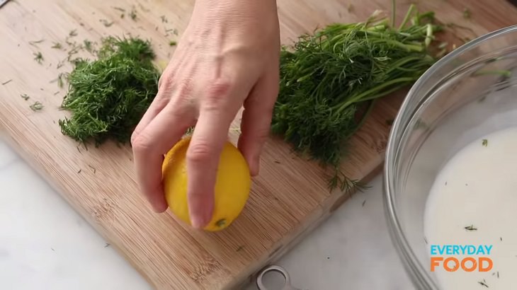 Simple and easy recipe for golden chicken with buttermilk marinade, bowl of marinade with lemon and fresh dill on a cutting board