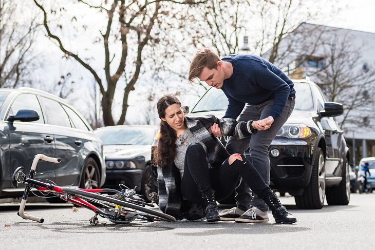 the dutch reach method of opening car doors for safety, man helping up woman after bike crash