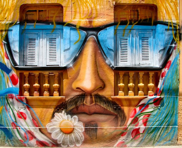 A highly decorative graffiti on a wall of a bearded man's face, wearing sunglasses with the eyes painted over the windows in Olinda, Pernambuco, Brazil