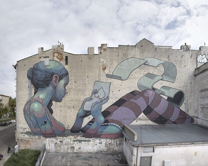 Beautiful Street art and graffiti murals from around the world, Aryz's mural in Lodz (2011), young lady painted in blue, semi-submerged and holding a paper with an upside down heart and other sheets of paper with papers in the air
