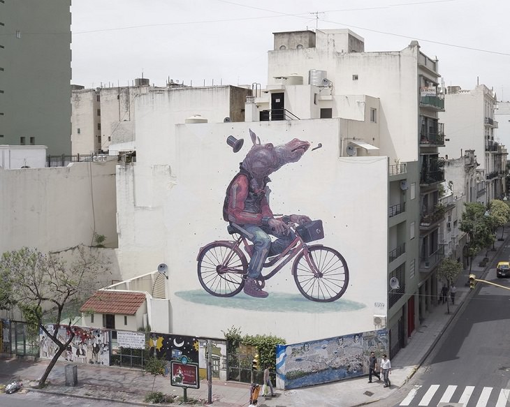 Beautiful Street art and graffiti murals from around the world, Aryz's mural in Argentina (2012), humanois creature with the body of a young man wearing a sweatshirt, having the head of a donkey on a bicycle