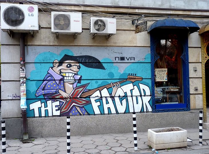 Beautiful Street art and graffiti murals from around the world, a man that appears to be a cartoon image of Elvis Presley holding an X-shaped guitar forming the words the X Factor