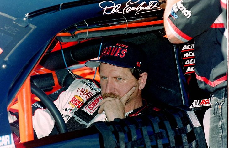 Top 19 NASCAR Race Drivers to Win Multiple Tracks, Dale Earnhardt Sr. in uniform sitting in a race car