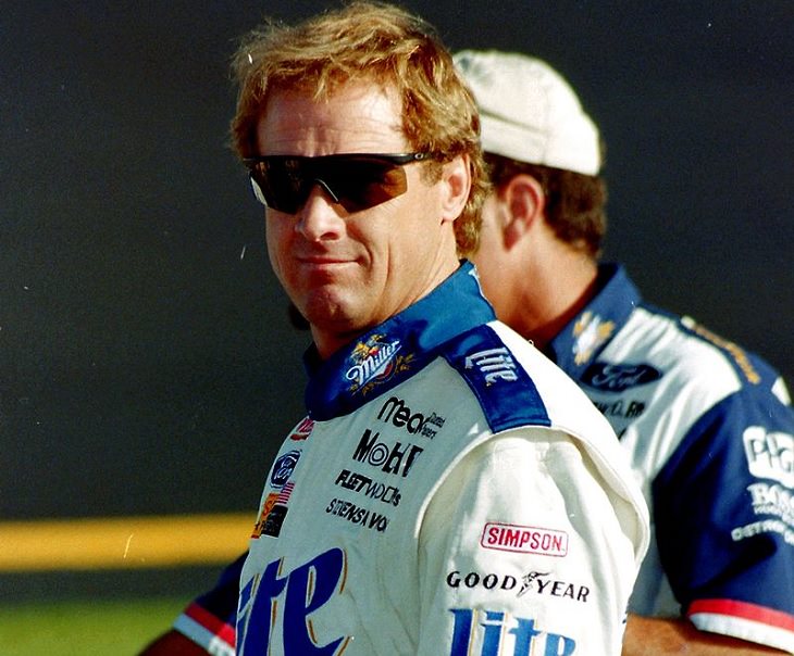 Top 19 NASCAR Race Drivers to Win Multiple Tracks, Rusty Wallace in a blue and white track suit on a race track site in 1997