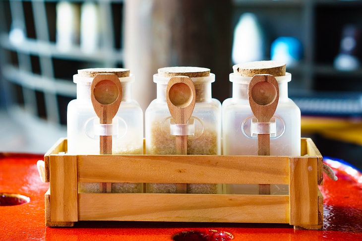 DIY homemade coffee creamer, three mason jars with wooden spoons containing sugar and coffee creamer, in a jar holder