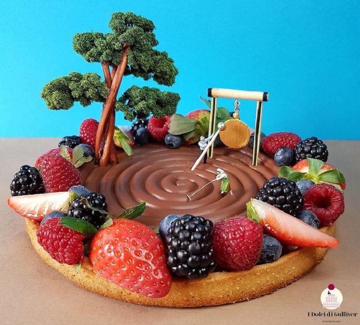 Beautiful Cakes Designed by Italian Chef, A vanilla cake with chocolate swirl on top and fruits alone the side, resembling a zen garden