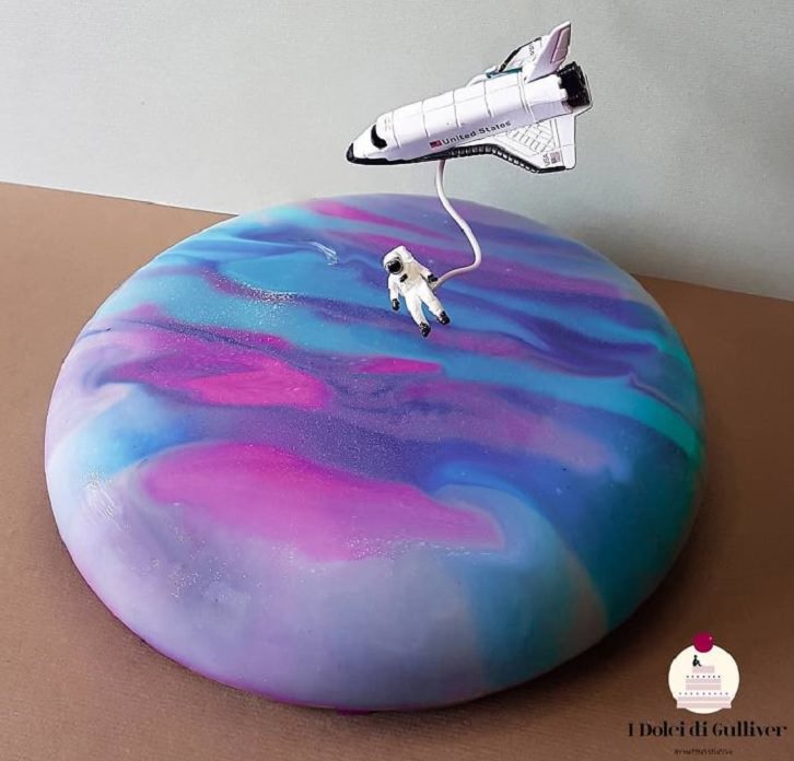 Beautiful Cakes Designed by Italian Chef, Circular cake with blue, pink and purple icing, and miniature astronaut and rocket on top of it