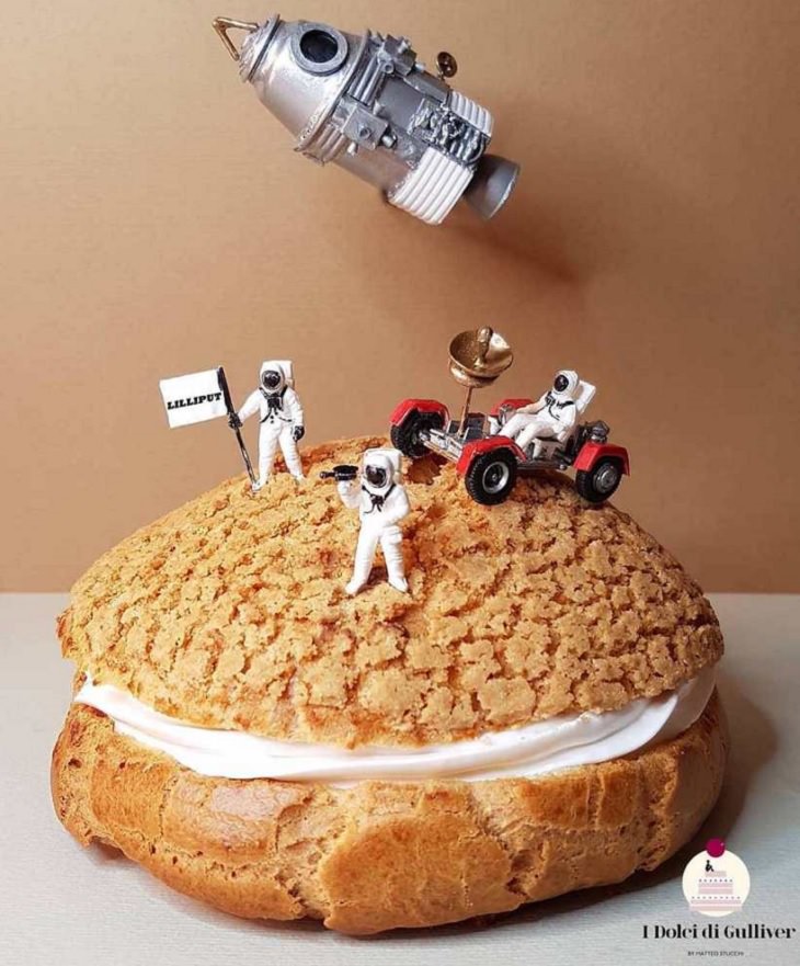 Beautiful Cakes Designed by Italian Chef, A cake sandwich with cream in the middle and a cookie crumble top, with miniature astronauts and rocket on top and a sign that says Lilliput