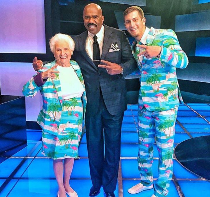 duo of grandmother and grandson, ross smith, wear fun costumes for social media, standing with steve harvey wearing blue beach-themed outfits 