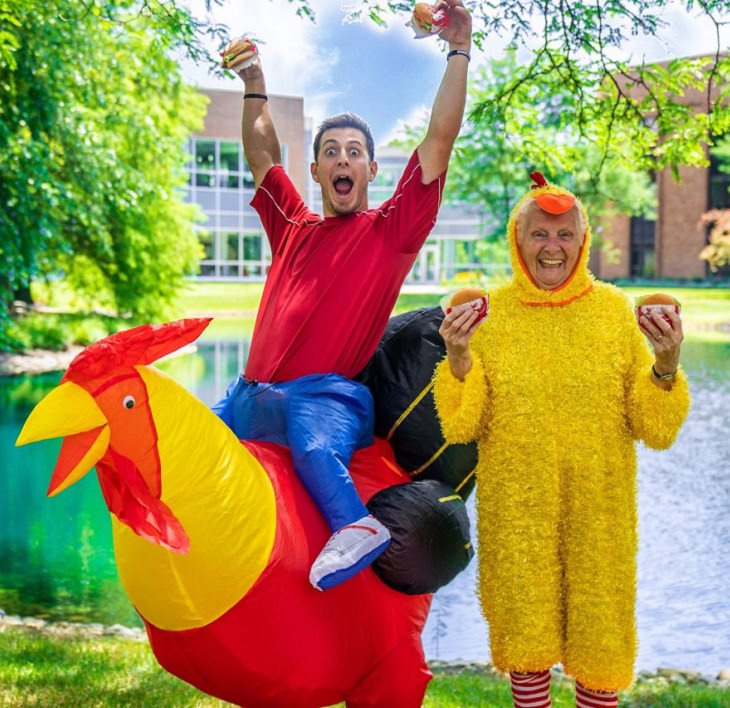 duo of grandmother and grandson, ross smith, wear fun costumes for social media, dressed in chicken outfits holding burgers