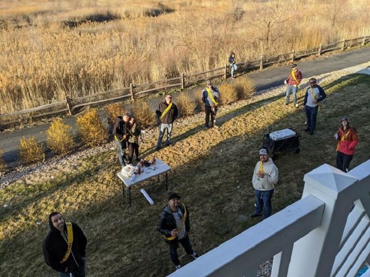 Funny and heartwarming pictures of birthday celebrations during the COVID-19 pandemic quarantine and lockdown, photo taken from top of multiple people standing six feet apart in the lawn below