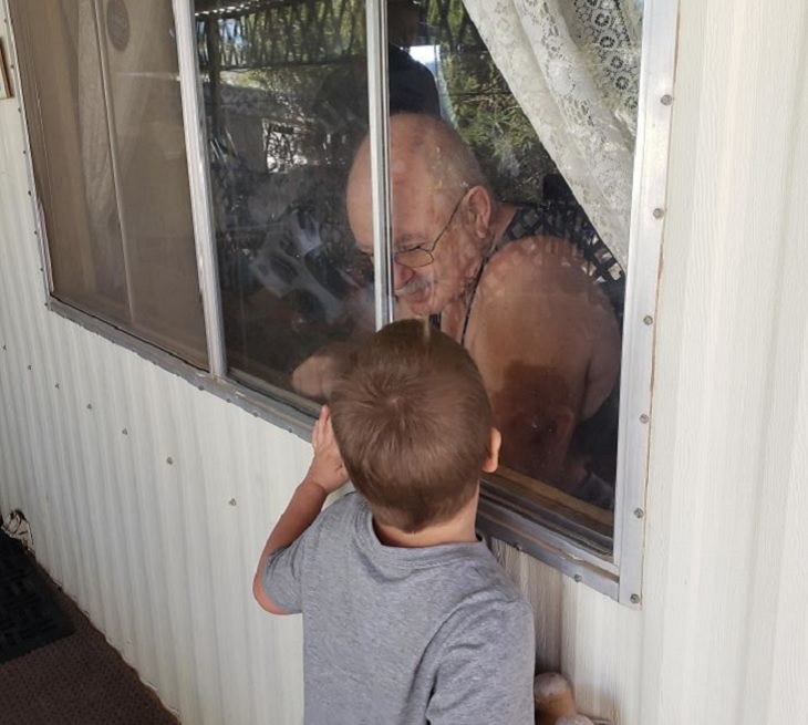 Funny and heartwarming pictures of birthday celebrations during the COVID-19 pandemic quarantine and lockdown, young boy outside window of grandfather