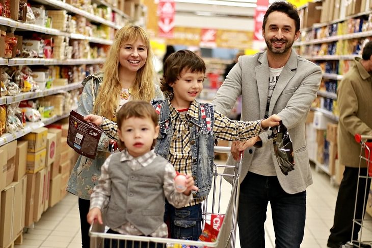 8 tips and tricks to help children develop healthy eating habits, Parents and two sons in a shopping cart at a grocery store.
