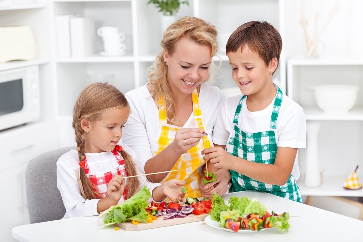 8 tips and tricks to help children develop healthy eating habits, Mother preparing healthy food with son and daughter