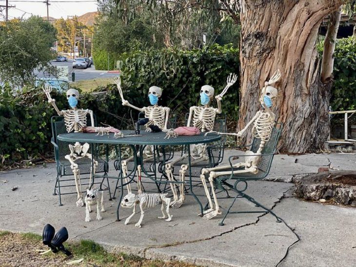 Creative and spooky halloween decorations from 2020, skeletons wearing masks sitting around a table with skeleton dogs