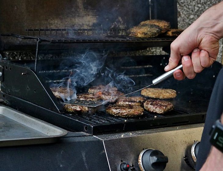 Common cooking mistakes and cooking tips, Person grilling burger patties pressing down on patty with spatula