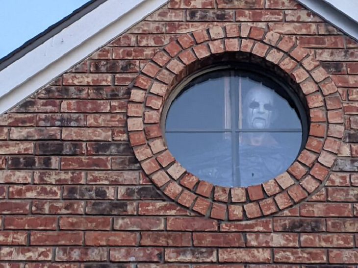 Creative and spooky halloween decorations from 2020, Creepy man with mask staring out of attic window