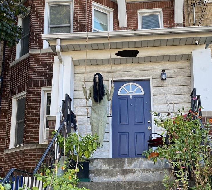 Creative and spooky halloween decorations from 2020, Mannequin in front of a house of young girl with long hair in a nightdress on a swing