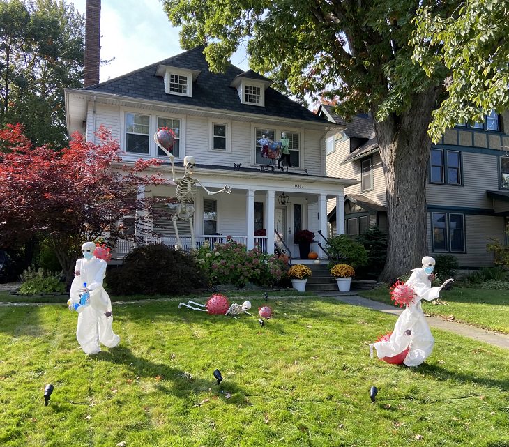 Creative and spooky halloween decorations from 2020, Skeletons, some wearing PPE, being hit by giant coronavirus shaped balls